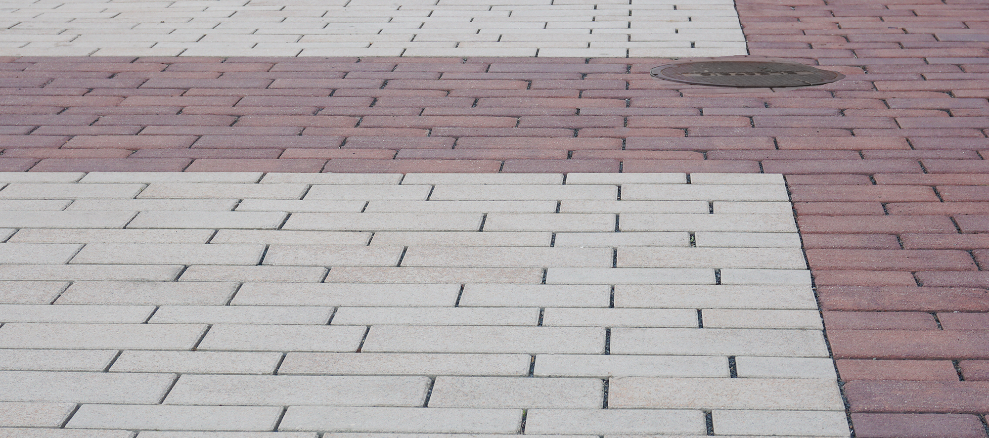 Red and beige Eco-Line pavers are placed in a running bond pattern to create distinct, patterned paver rugs.